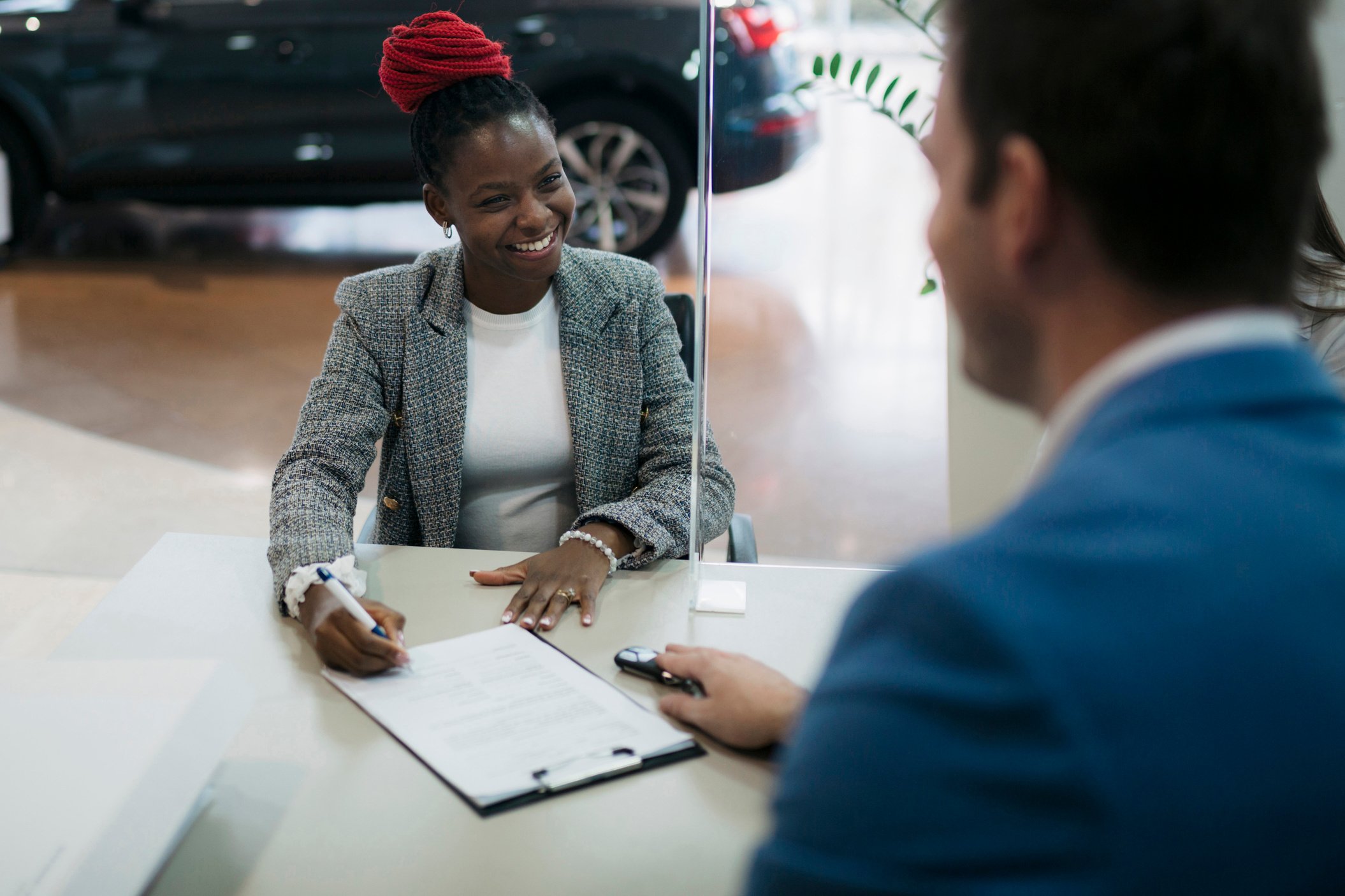 Woman customer signing a contract at car dealership